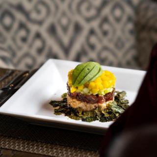 A beautifully plated gourmet dish featuring layers of avocado and mango.