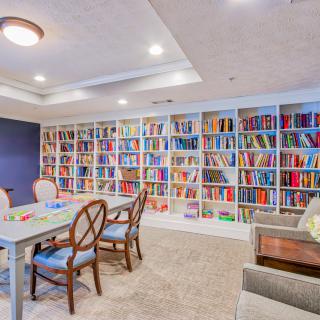 A cozy library room with bookshelves lining the wall, featuring a table and chairs for reading or studying.