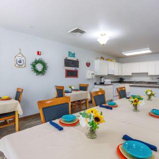 A bright dining area with neatly set tables, colorful plates, and floral decorations.