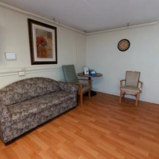 A cozy living space featuring a couch, two chairs, a small table, and wall art.