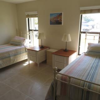 A simple bedroom with two twin beds and ample natural light.
