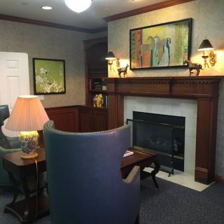A cozy living room featuring a fireplace, artwork, and comfortable seating.