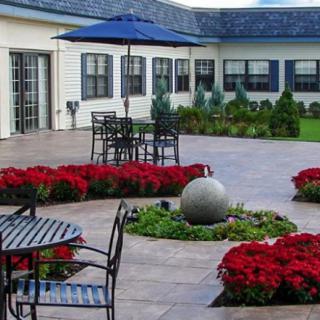 A beautifully landscaped courtyard with outdoor seating, surrounded by vibrant red flowers.