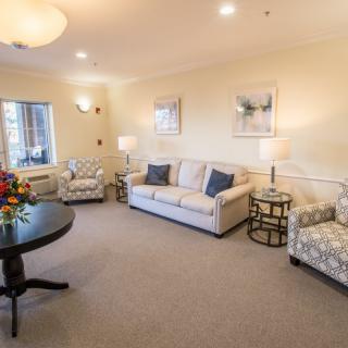 A cozy living room with comfortable sofas and armchairs, decorated with framed artwork and ambient lighting.