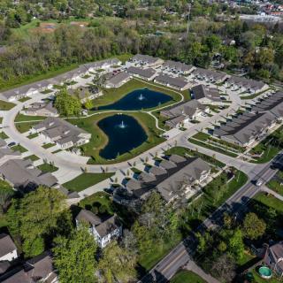 Aerial view of a residential neighborhood featuring ponds with fountains surrounded by houses and greenery.