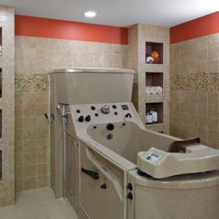 A spa room featuring a therapy tub with tiled walls and shelves.