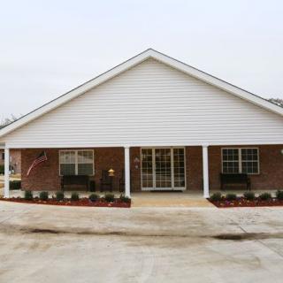 A single-story brick residential building with a covered front porch and landscaped yard.