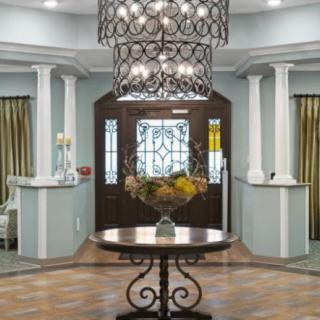 Elegant entryway with a chandelier and floral centerpiece.