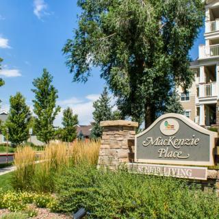 Entrance sign to a residential apartment complex surrounded by well-maintained landscaping and trees.