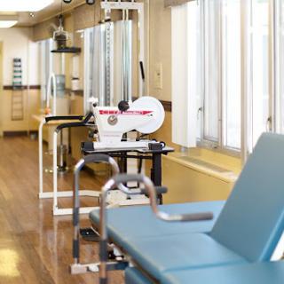 A well-lit physical therapy room featuring various exercise equipment.