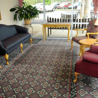 A cozy lobby area featuring a couple of sofas, a chair, and a coffee table, illuminated by natural light.