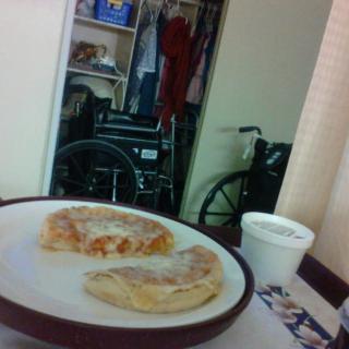 A plate with pastries and a cup in a room with a wheelchair in the background.