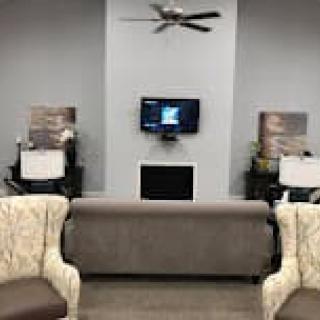 A modern waiting room with comfortable seating and a wall-mounted television.