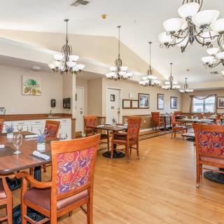 An elegant dining room with ornate chandeliers and wooden chairs featuring intricate designs.