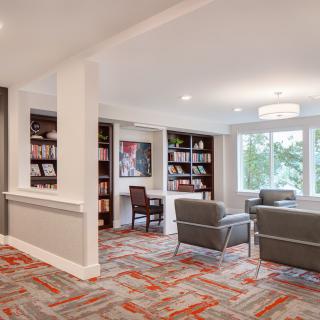 A modern living room with comfortable seating, bookshelves, and large windows.
