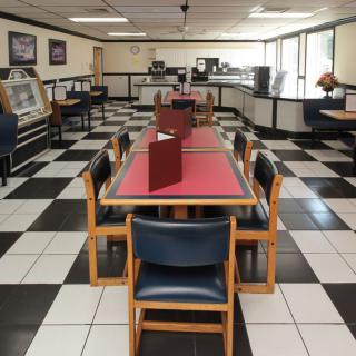 An empty diner with checkered flooring and neatly arranged tables and chairs.