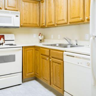 A kitchen with wooden cabinets, featuring a stove, microwave, and dishwasher.