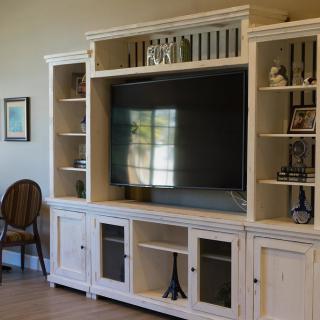 A cozy living room entertainment center with a large TV and surrounding shelves.