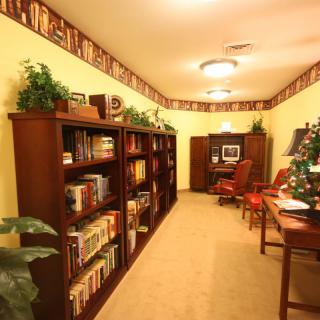 A cozy home office with bookshelves lining the walls and a computer desk at the far end.