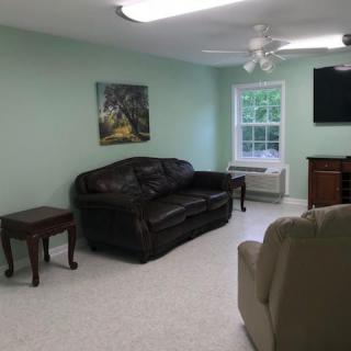 A cozy living room with a dark sofa, side tables, and a wall-mounted television.