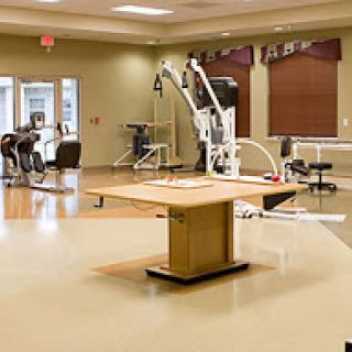 A well-equipped physical therapy room featuring various rehabilitation machines and a central workspace.
