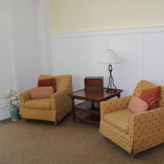 A cozy living room setting with two armchairs, a side table, and a lamp.