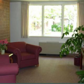 A cozy living room with comfortable armchairs and a large window overlooking a garden.