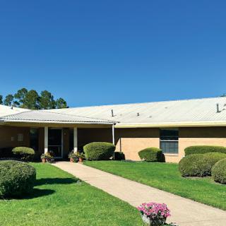 A well-maintained building with neatly trimmed shrubs and a clear blue sky.