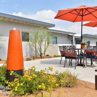 A well-designed patio with furniture and an orange umbrella, surrounded by garden landscaping.