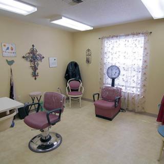 An interior view of a hair salon with various chairs, a hair dryer, and decorative items on the wall.