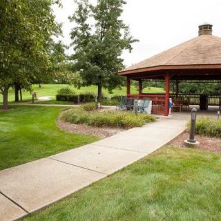 A serene park setting with a gazebo and a paved pathway surrounded by lush greenery.
