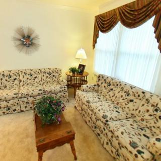A cozy living room with floral couches, a wooden coffee table, and traditional decor.