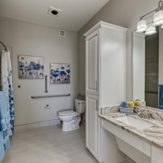 A modern bathroom interior featuring a toilet, sink with cabinetry, and decorative elements.