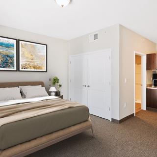 A modern bedroom interior with a neatly made bed, artwork on the wall, and warm lighting.
