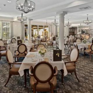 An elegant restaurant dining room with neatly arranged tables and classic chandeliers.