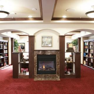 A cozy library interior with a fireplace and surrounding bookshelves.