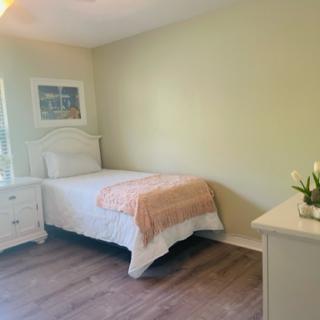 A cozy and minimalist bedroom with light green walls and simple furnishings.