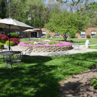 A serene garden with a flower bed, patio furniture, and green surroundings.