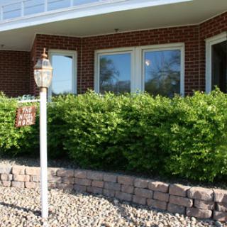 A well-maintained house exterior featuring greenery and a lamp post.