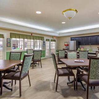A cozy dining area with tables and chairs adjacent to a kitchen space.