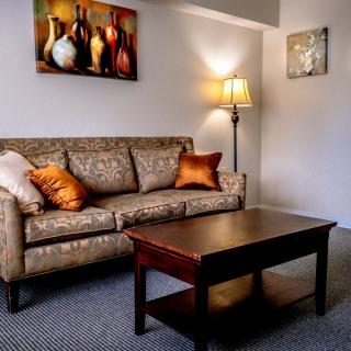 A cozy living room with a patterned sofa, wooden coffee table, and warm lighting.