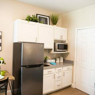 A small modern kitchen with white cabinets, a refrigerator, and a microwave.