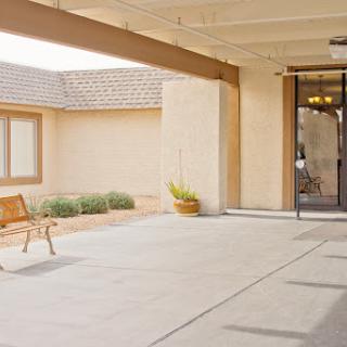 A peaceful entrance to a building featuring a bench and landscaped surroundings.