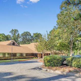 A suburban building surrounded by trees and a driveway under a clear blue sky.