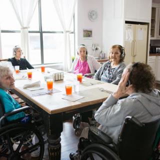 A group of elderly individuals enjoying a social gathering around a dining table in a care facility.