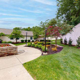 A beautifully landscaped garden with a winding pathway, surrounded by lush greenery and trees.