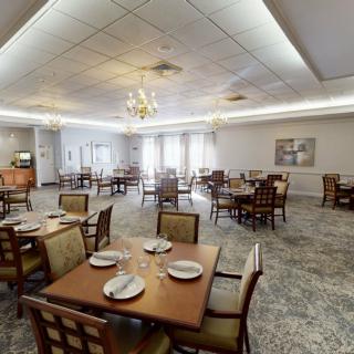 A spacious dining room with elegantly set tables and a chandelier.