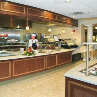 A clean and well-maintained cafeteria with a serving counter and kitchen staff.