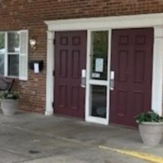 A building entrance with double doors and potted plants.