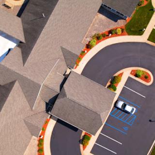 An aerial view showcasing a modern building complex with a well-maintained parking lot and landscaping.